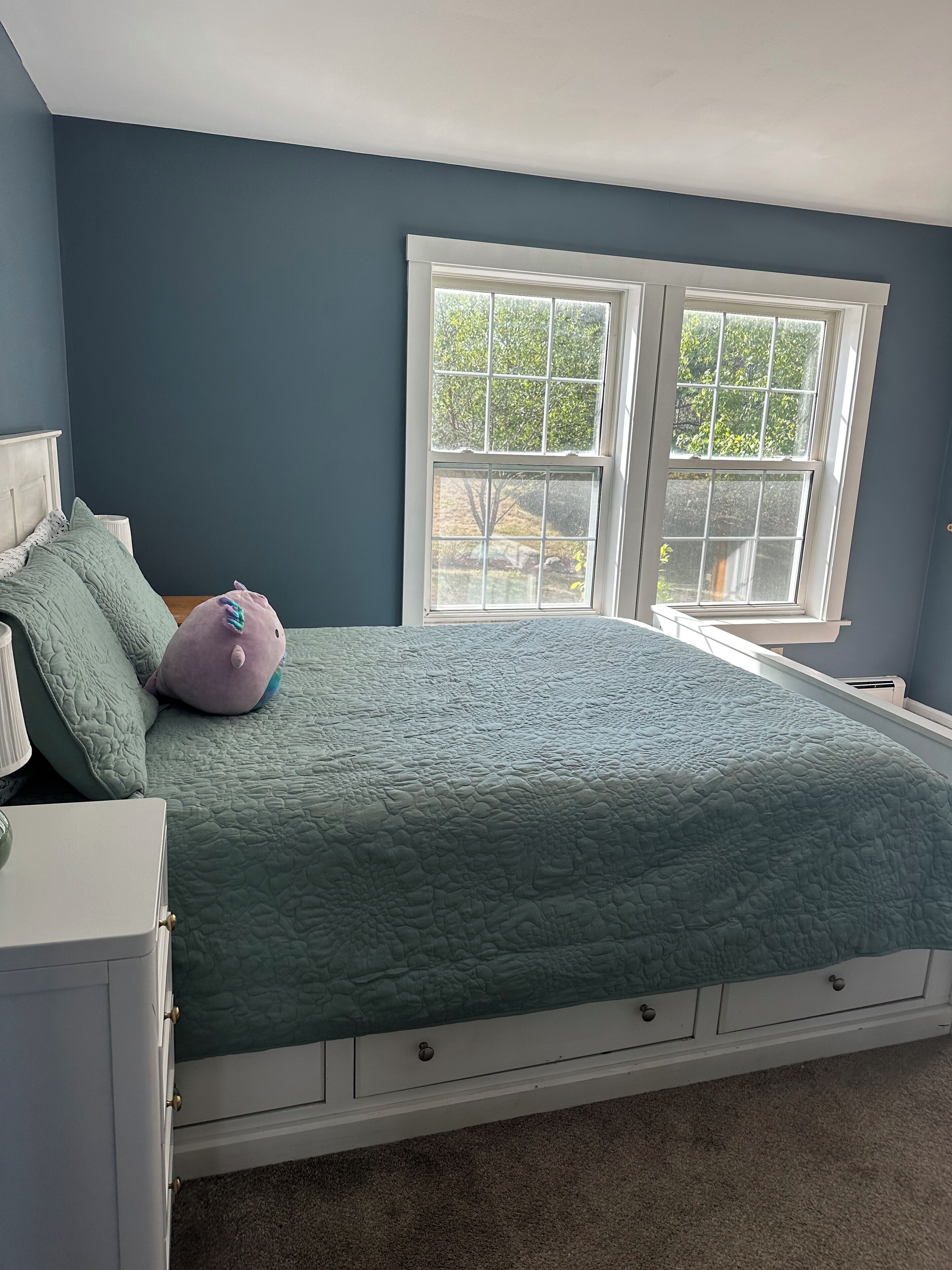 Une chambre à coucher avec un lit, une table de chevet et une fenêtre.