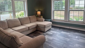 Una sala de estar con un sofá modular, ventanas amplias y una lámpara de pie.