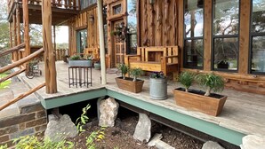 A wooden cabin with a porch, stone steps, and potted plants.