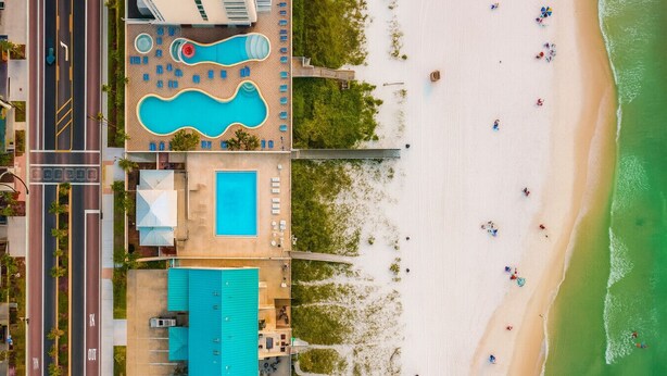 Vista aerea di un resort con diverse piscine, una spiaggia e un parcheggio.
