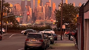 A cityscape with tall buildings, a street with parked cars, and traffic lights. - Modern Studio: minutes to NYC/Views, 4 miles from World Cup - MetLife Stadium (Weehawken Township)