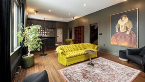 Un salon moderne avec un canapé jaune, une table basse ronde et un grand tableau accroché au mur.
