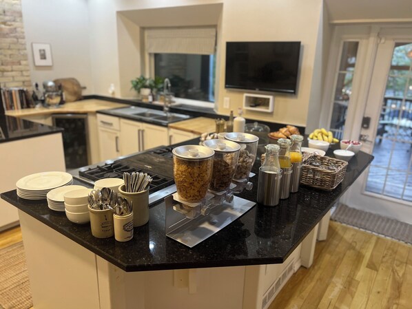 A kitchen with a black countertop, white cabinets, and a TV mounted on the wall. - No.5 East (Winnipeg)