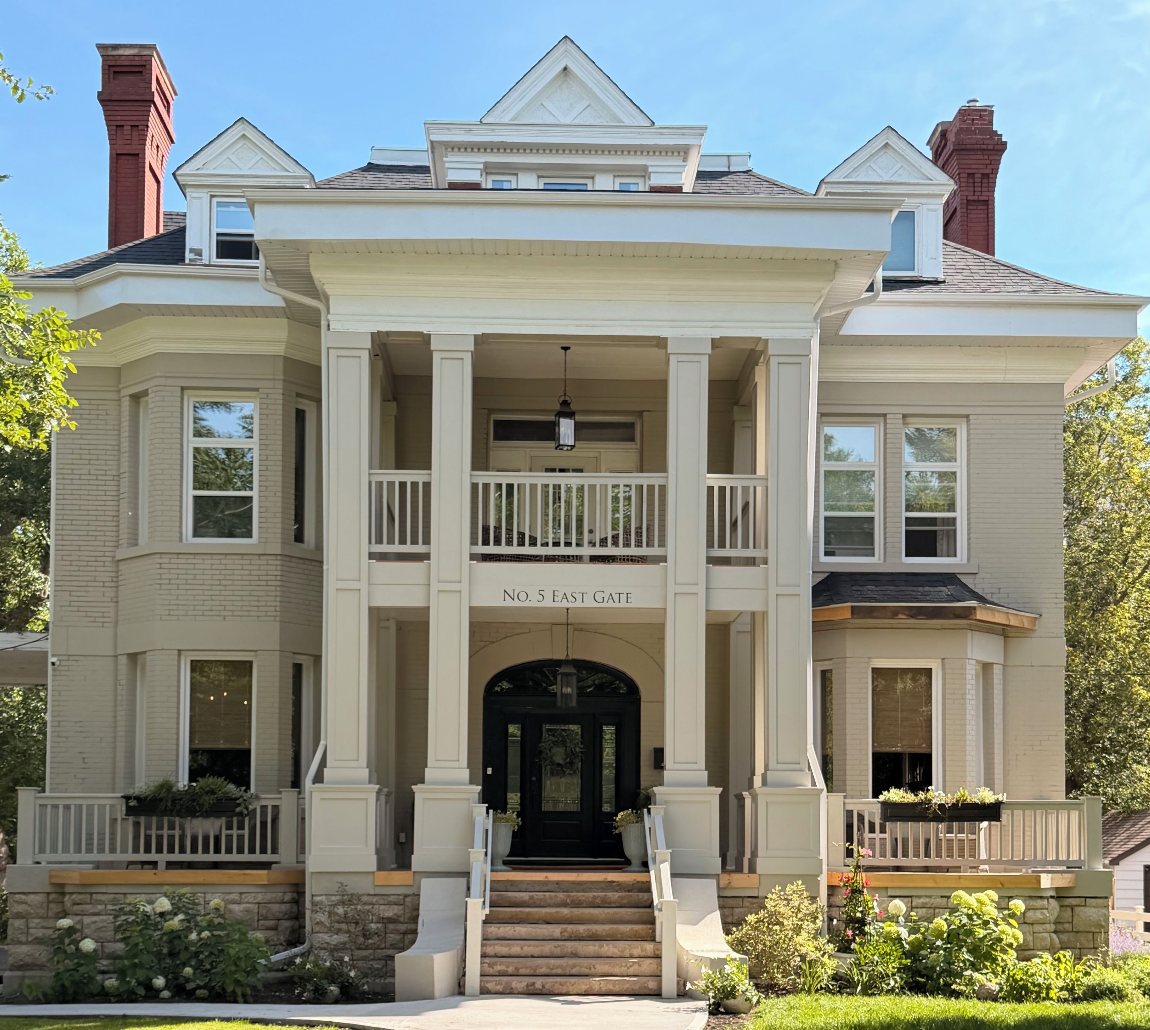 A large, stately building with a central entrance, multiple balconies, and a nameplate indicating 'No. 5 East Gate.'