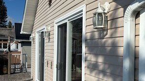 A house with a wooden deck, sliding glass doors, and exterior lighting fixtures.