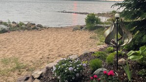 Una playa con un jardín que incluye una escultura de metal decorativa y plantas con flores.