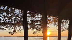 Una mesa y sillas junto a una ventana con vista a una puesta de sol sobre el agua.