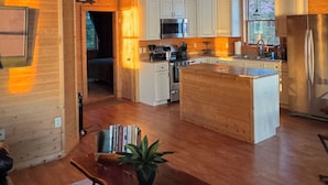 A spacious kitchen with white cabinets, stainless steel appliances, and a wooden ceiling fan.