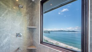 Un baño con un ventanal grande que da a una playa y al océano.
