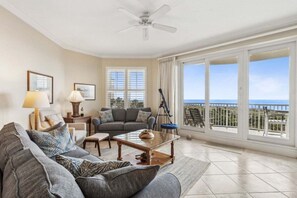 A living room with a sofa, coffee table, and a balcony with a view. - Ocean Place 12 ~ Wave Watcher (Fernandina Beach)