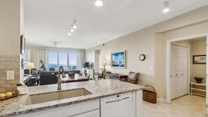 A modern kitchen with a granite countertop, white cabinetry, and a built-in dishwasher. - Ocean Place 12 ~ Wave Watcher (Fernandina Beach)