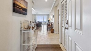 A hallway with a white door, a white railing, and a view into a dining area. - Ocean Place 12 ~ Wave Watcher (Fernandina Beach)