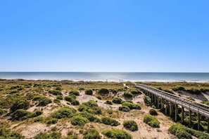 A beach with a wooden boardwalk leading to the water, surrounded by dunes and vegetation. - Ocean Place 12 ~ Wave Watcher (Fernandina Beach)