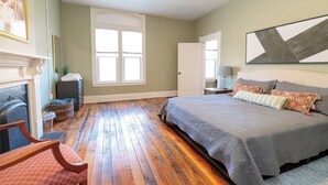 A bedroom with a large bed, a fireplace, a window, and a door. - Salem Boutique Downtown 3BDRM Suite (Salem)
