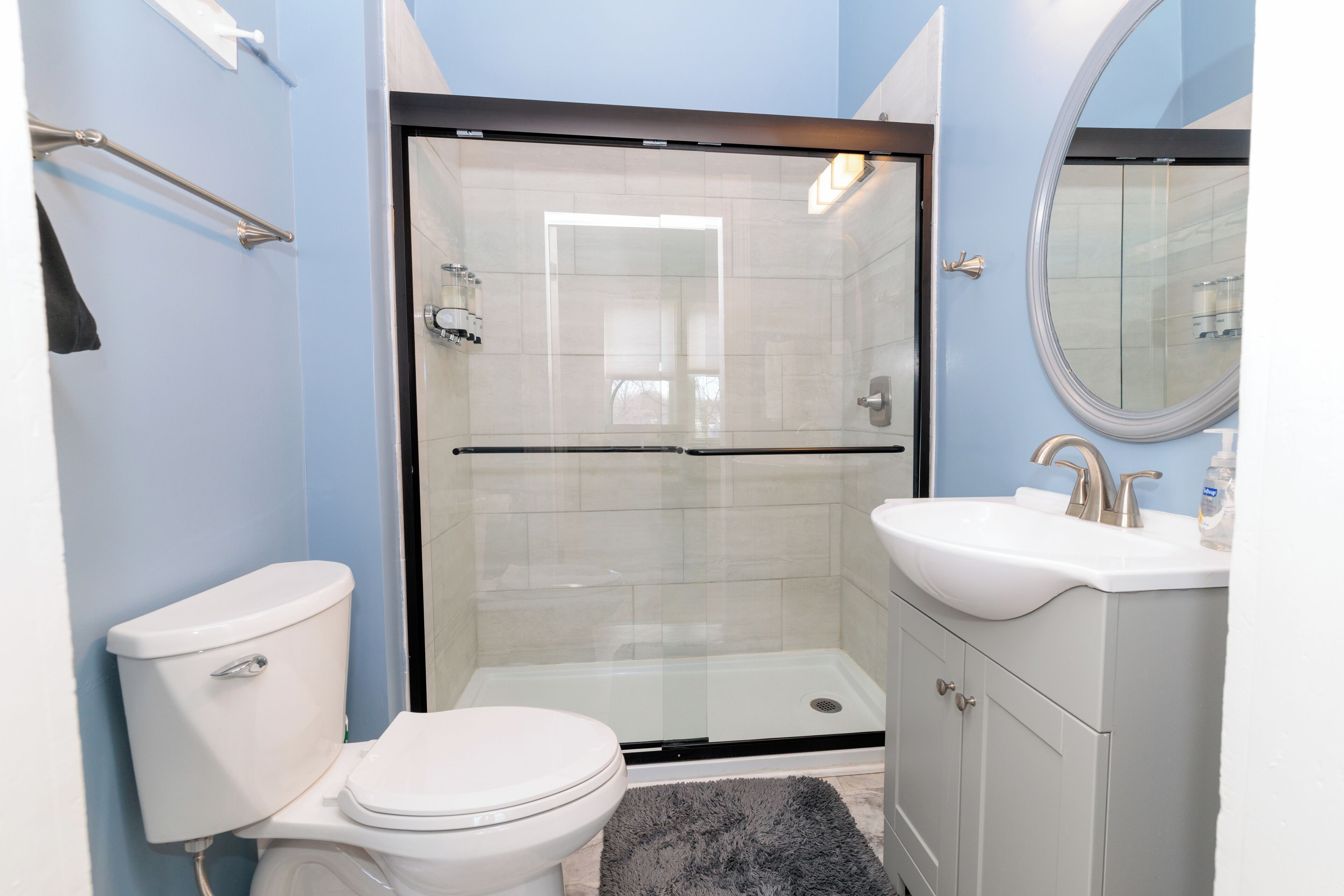 Een moderne badkamer met een toilet, een douche met glazen wanden en een wastafel met spiegel.