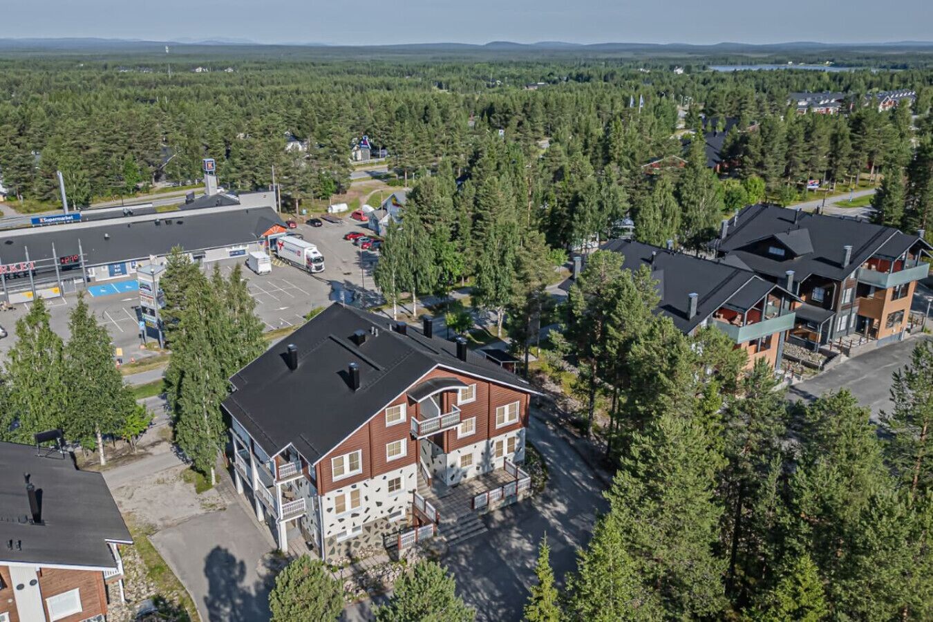 A residential area with a mix of single and multi-story houses, surrounded by dense forest.