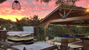 A covered outdoor patio with a hot tub, seating area, and a fire pit. - Tiny cabin/guest house with hot tub and pool surrounded by nature (Lakehills)