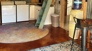 A rustic kitchen with a wooden ladder, vintage appliances, and a colorful rug. - Tiny cabin/guest house with hot tub and pool surrounded by nature (Lakehills)