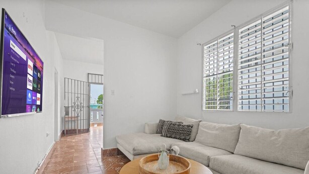 A living room with a sofa, a coffee table, and a TV mounted on the wall.