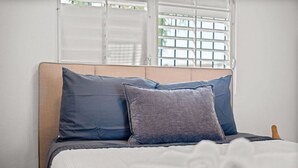 A bed with a wooden headboard, two pillows, and a white bedspread.
