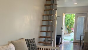 Un dormitori amb un llit, una escala i vista a l'exterior.
