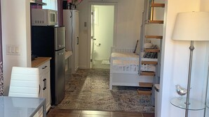 Una cuina compacta amb microones, nevera i una petita zona de dinar amb taula i cadires.