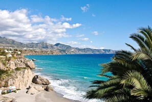 A coastal landscape with a beach, rocky cliffs, and a clear blue sea. - Beautiful apartment with a view of the Mediterranean Sea, just a few minutes' walk from the beach. (Mijas)