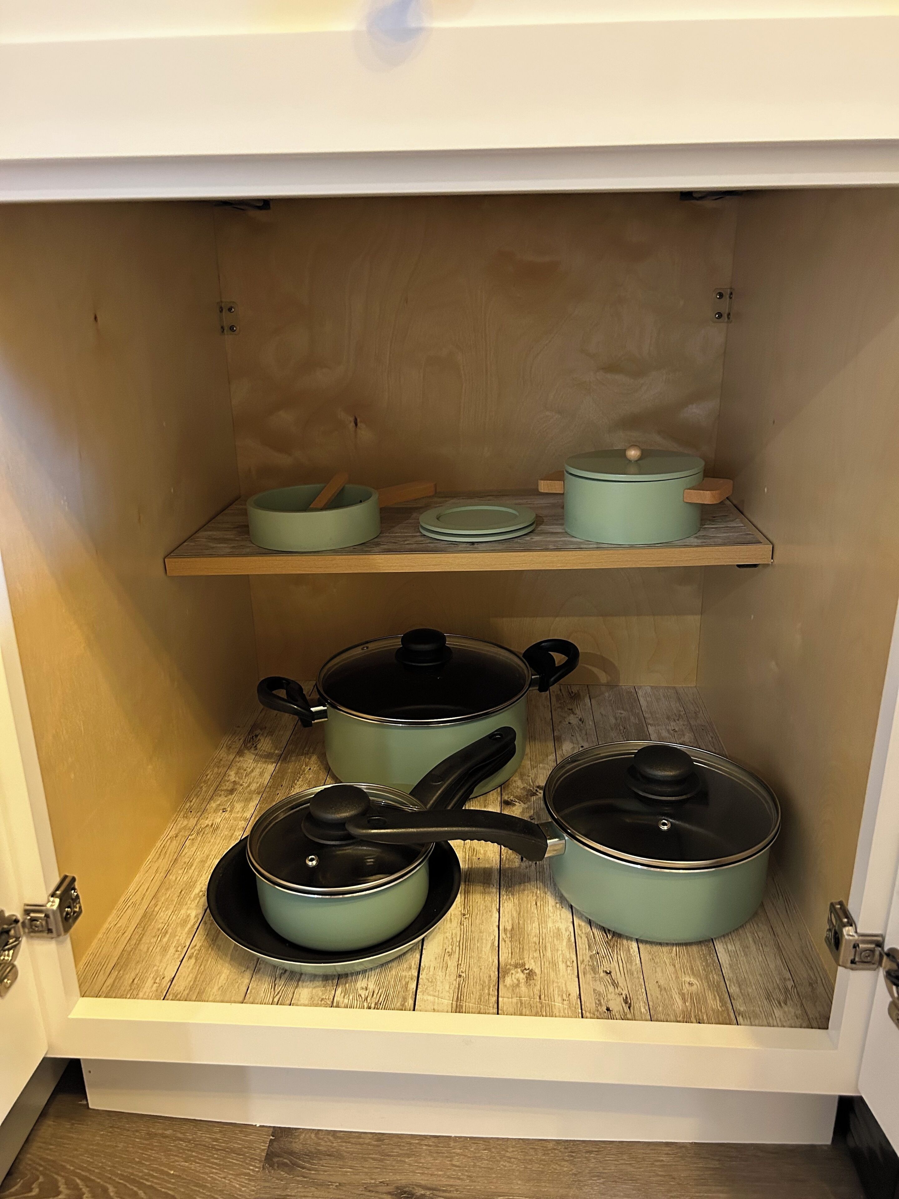 Ein Küchenschrank mit einer Holzablage und drei Töpfen.