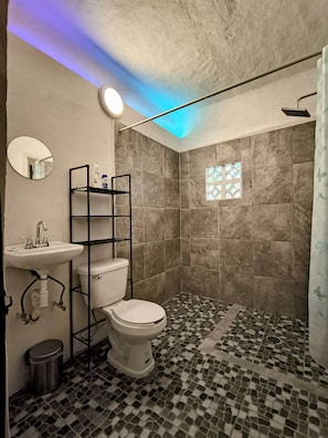 A bathroom with a tiled floor, a toilet, a sink, and a shower. - CASA ROSA SAYULITA (Sayulita)