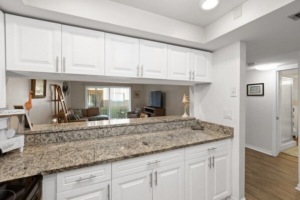 A kitchen with white cabinets, granite countertops, and a view to the dining area.