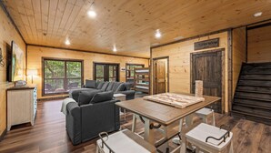 A cozy cabin interior with a sofa, dining table, and chairs. A sign indicates a laundry room.