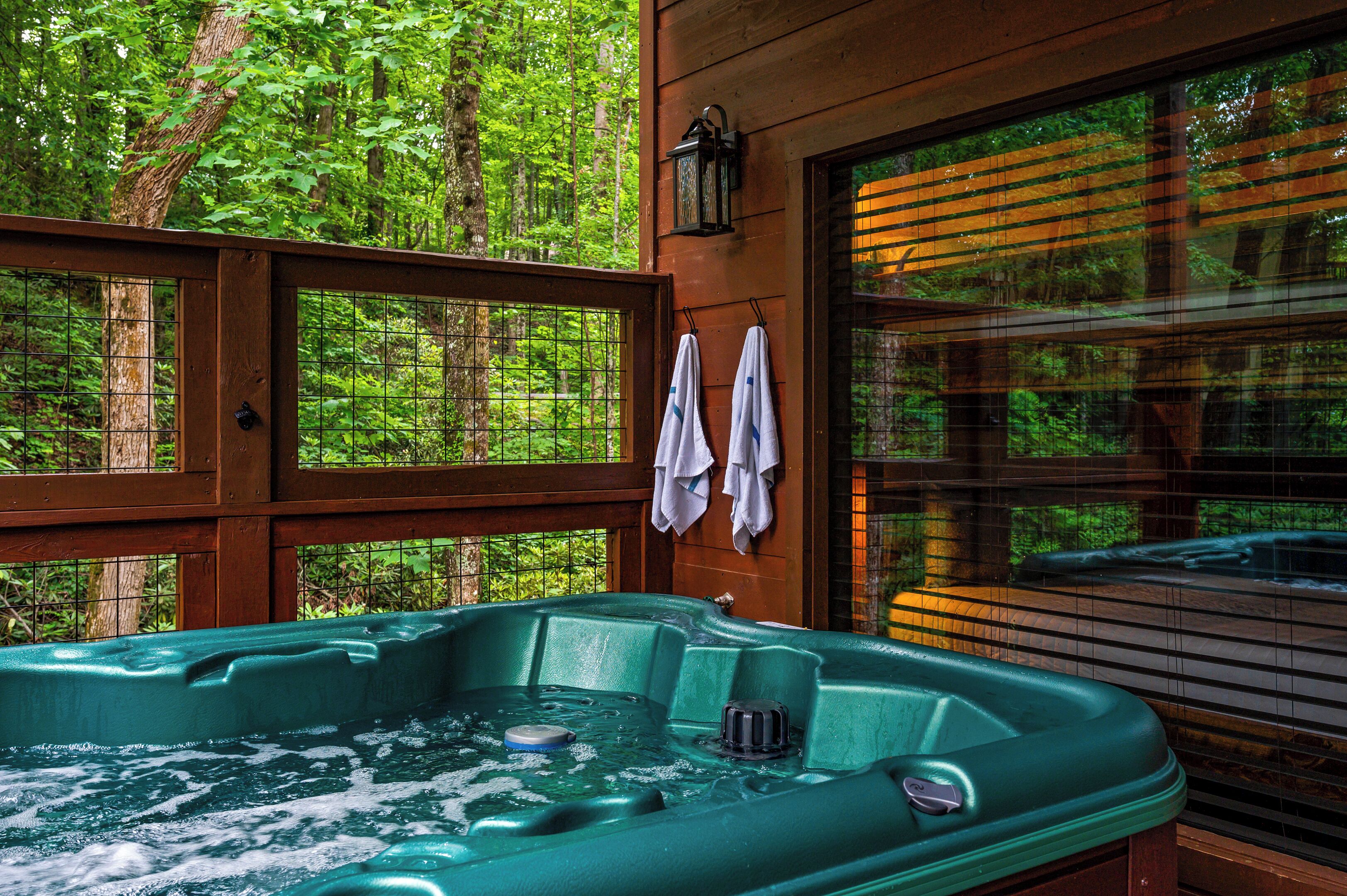 A hot tub with a wooden deck and a view of a forest.