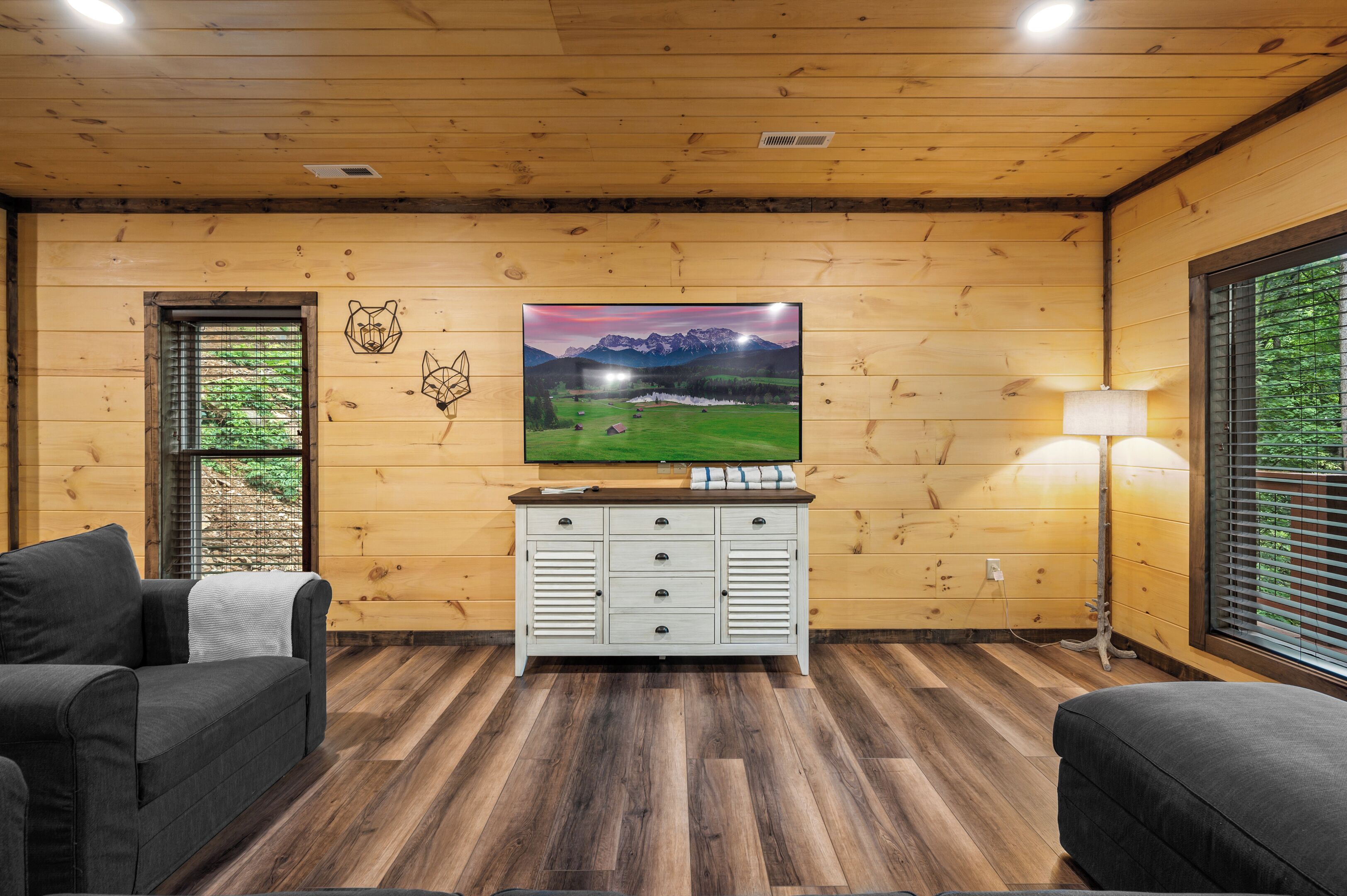 A wooden-paneled room with a television on a cabinet, a sofa, and a lamp.