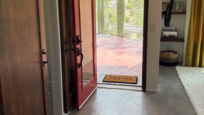 Una habitación con puerta corredera que da a un espacio exterior con cactus y vistas al desierto.