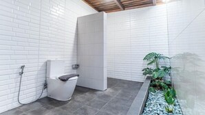 Un baño con azulejos blancos estilo metro, una ducha y una pequeña planta.