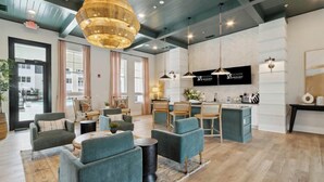 Een moderne hotellobby met zithoeken, een keuken en een grote kroonluchter.