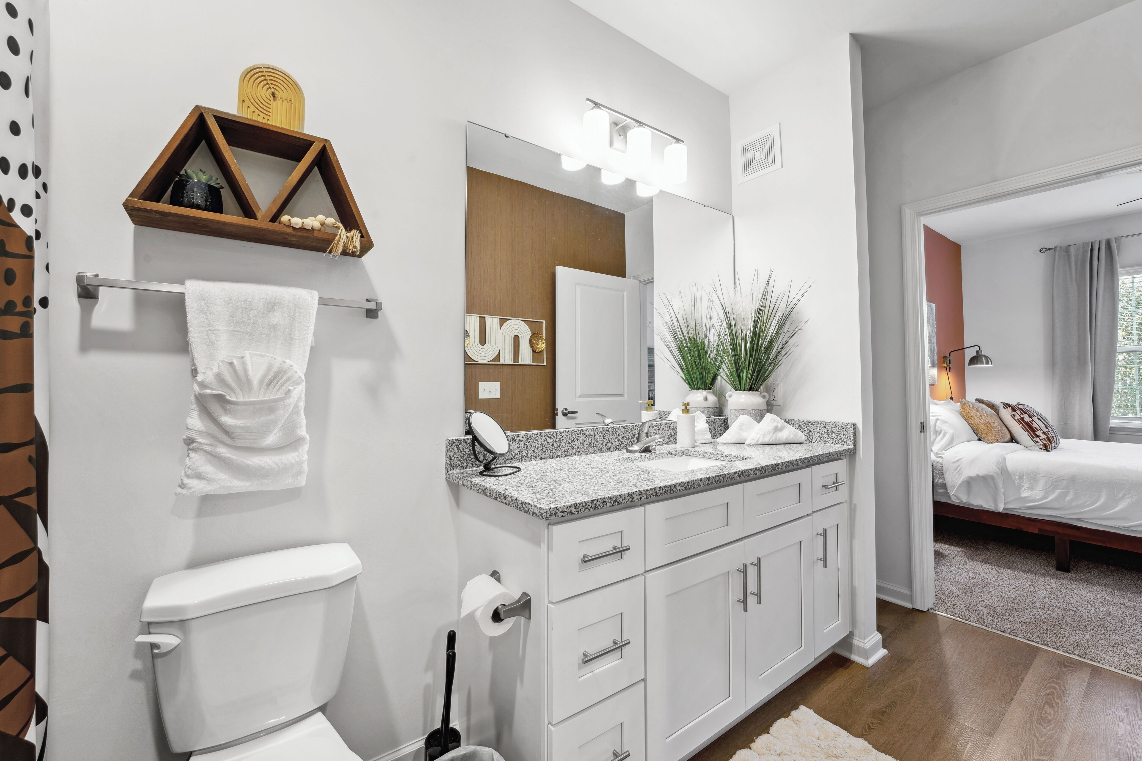 Un baño moderno con un inodoro blanco, un tocador con espejo y un perchero para toallas.