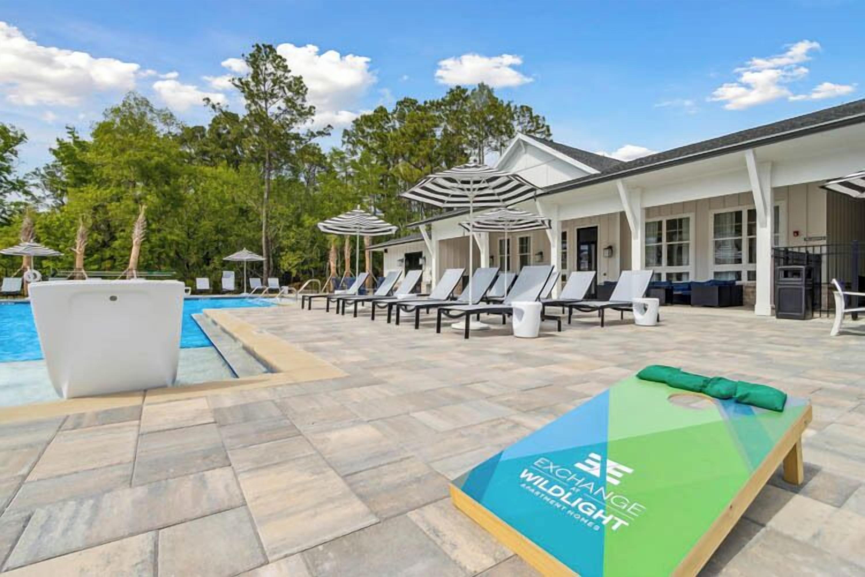 A poolside area with lounge chairs, umbrellas, and a bench with a logo.