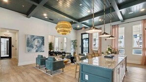 Een ruime woonkamer met een groot kookeiland, moderne meubels en een hoge plafond met zichtbare balken.