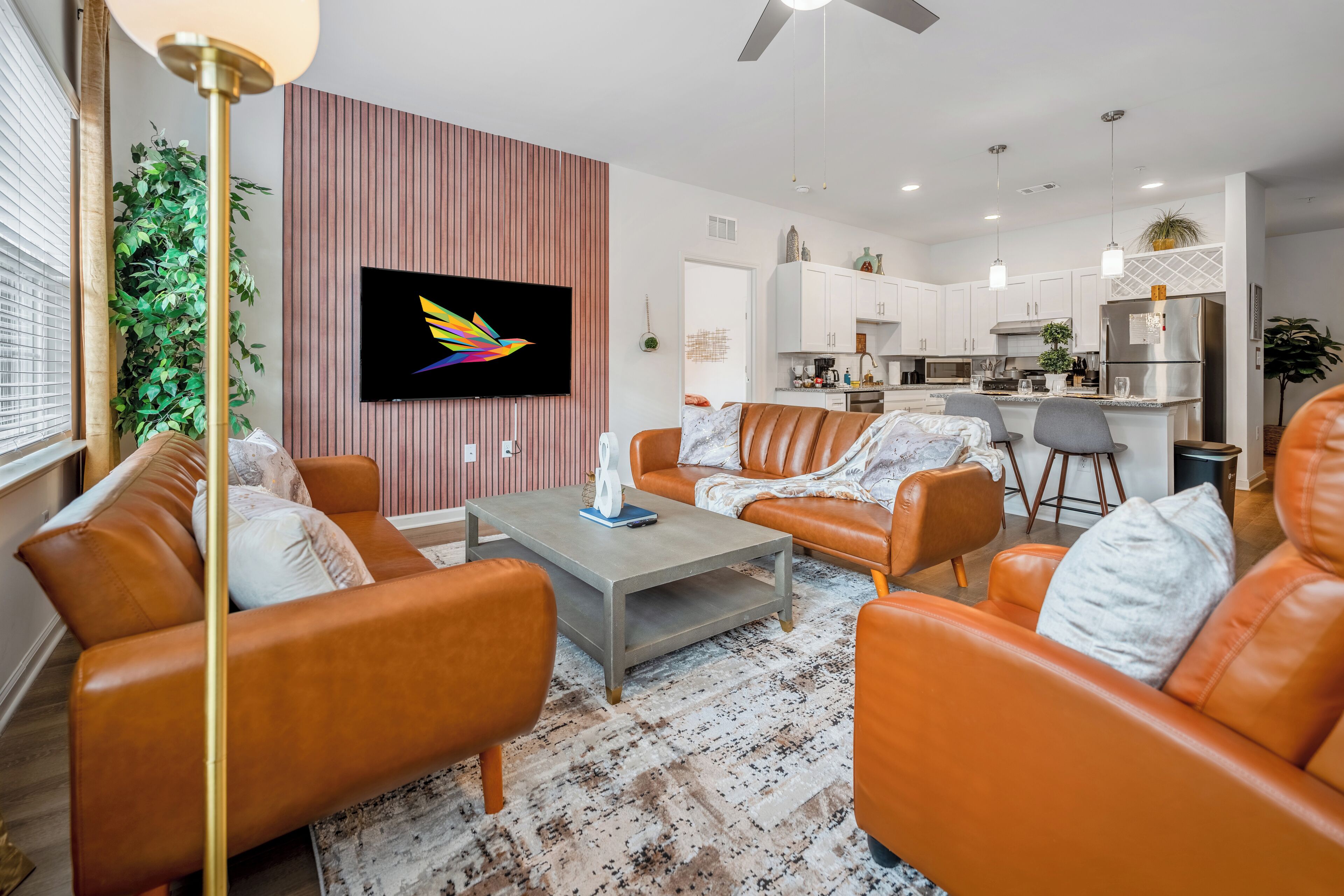 A modern living room with orange leather sofas, a coffee table, and a TV mounted on a wall.