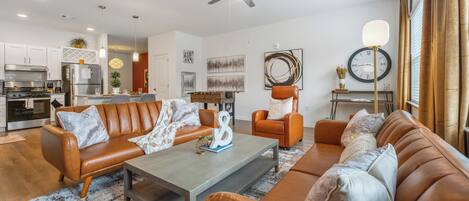 A modern living room with leather sofas, a coffee table, and a dining area with a foosball table.