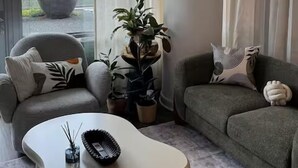 Ein modernes Wohnzimmer mit einem Bogensofa, zwei Sofas und einem großen Fenster mit durchscheinenden Vorhängen.