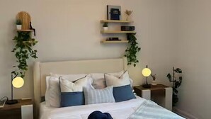 Ein ordentlich eingerichtetes Schlafzimmer mit einem Bett, Nachttischen und Wandregalen.