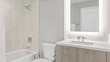Ein Badezimmer mit Badewanne, Toilette und Waschtisch mit Spiegel.