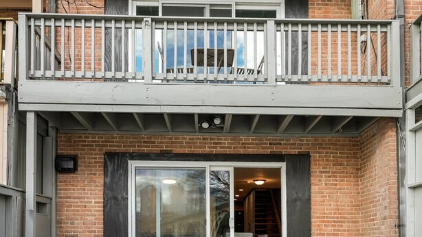 A two-story building with a balcony, a sliding glass door entrance, and a brick facade. - Georgetown 4BR Waterfront Townhome | Potomac Views & Parking (Washington)