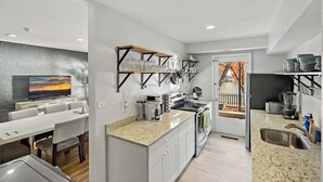 Eine moderne Küche mit weißen Schränken, Granit-Arbeitsplatten und einem Essbereich mit einem weißen Tisch und Stühlen.
