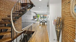 Ein modernes Interieur mit einer Wendeltreppe, Holzböden und Backsteinwänden.