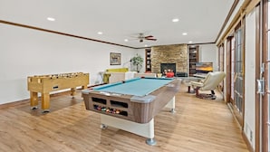 Un amplio salón con mesa de billar, mesa de futbolín y un cómodo espacio de estar.