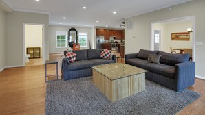Ein geräumiges Wohnzimmer mit zwei Sofas, einem Couchtisch und einer Küche im Hintergrund.