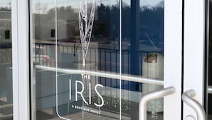 Une porte en verre ornée d’un logo et d’une inscription indiquant « The Iris Boutique Hotel ».